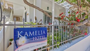 A hotel sign, a staircase, and a railing with plants and flowers.
