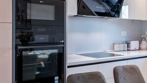 Une cuisine moderne dotée d’appareils électroménagers intégrés, d’un téléviseur à écran plat et d’un coin repas avec une table dressée pour deux personnes.