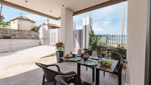 Un espace de restauration en plein air avec une table dressée pour deux personnes, des chaises et une vue sur la mer.