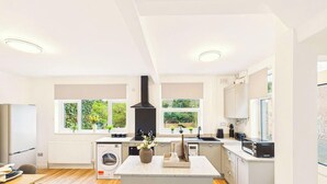 A modern kitchen with a central island, built-in appliances, and large windows.