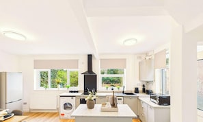 Een moderne keuken met een centraal eiland, geïntegreerde apparatuur en grote ramen.