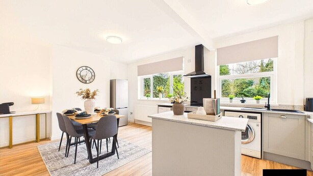 A modern kitchen with a central island, built-in appliances, and large windows.