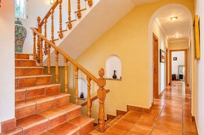 A staircase with wooden balusters and terracotta tiles, leading to a hallway with a tiled floor and a decorative vase on a shelf. - Villa 'Emilio' with Sea View, Private Pool and Wi-Fi (Alicante)