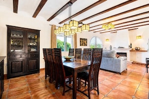 A dining area with a wooden table and chairs, a cabinet with glass doors, and a fireplace. - Villa 'Emilio' with Sea View, Private Pool and Wi-Fi (Alicante)