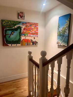 A staircase with white balusters and a wooden handrail, leading to a landing with a colorful mural and a framed photograph on the wall. - Pay30nghts get up tp Extra 59 Free (London)