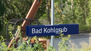 A street sign reading 'Bad Kohlgrub' with a metal fence and potted plants in the foreground. - Apartment for 6 Guests (88 m²) in Bad Kohlgrub (Bad Kohlgrub)
