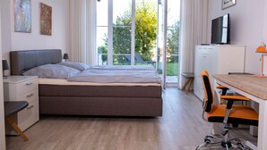 A bedroom with a bed, a desk, a chair, a TV, and a window with curtains. - Apartment for 6 Guests (88 m²) in Bad Kohlgrub (Bad Kohlgrub)
