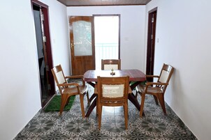 Comedor con mesa redonda y seis sillas, puerta de madera con panel de vidrio y baldosas de suelo con diseño.