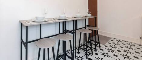 A bar area with stools, a long table, and a patterned floor.