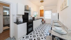 A modern kitchen with white cabinets, a black stove, and a dining area with a table set for four. - Free Parking Sleeps 2 Central Location (Reading)