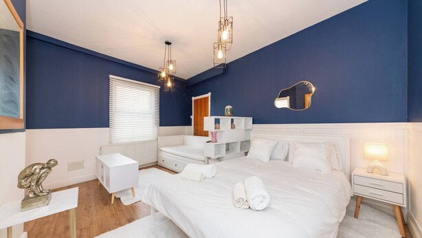 A bedroom with a large bed, bedside tables, a dresser, a mirror, and a hanging light fixture. - Free Parking Sleeps 2 Central Location (Reading)