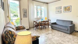 Una sala de estar con un sofá, una mesa con sillas, una lámpara y un sofá gris.