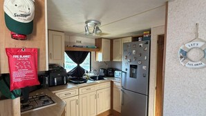 Una cocina compacta equipada con estufa a gas, refrigerador y microondas.