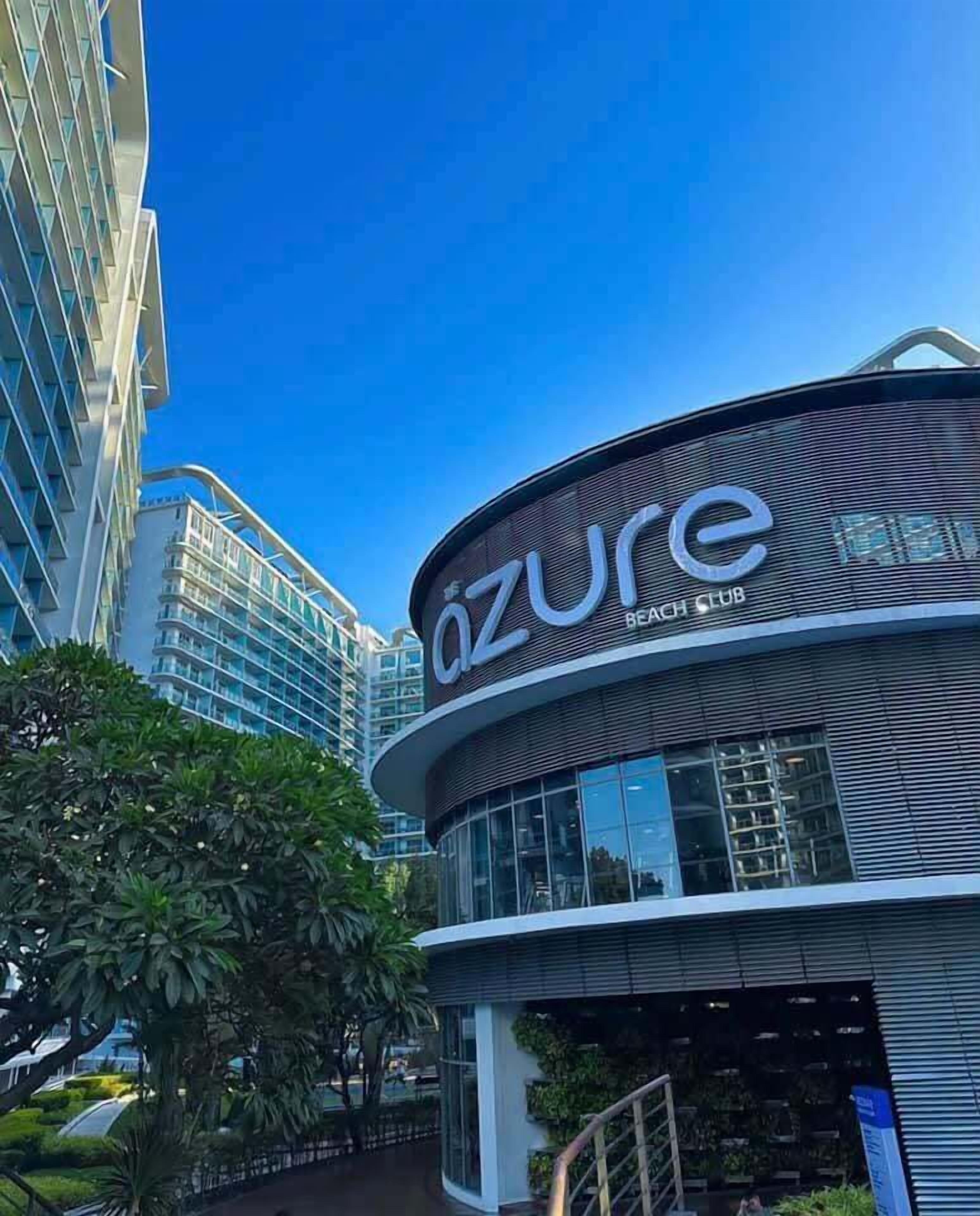 Un edificio moderno con el letrero 'Azure Beach Club', que indica un hotel o resort.