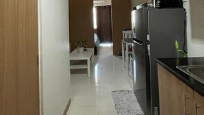 A narrow hallway leading to a bedroom with a bed and a window. - Her Casa Stays (Paranaque)