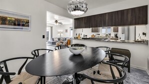 Un espace repas moderne avec une table ronde, des chaises noires, un grand saladier au centre et un luminaire sphérique original.