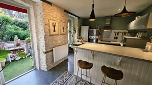 A modern kitchen with a stone wall, a bar area, and a view of a garden. - Duplex standing 3 beds sea view - terrace/ Cancale (Cancale)