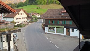 Straßenansicht mit Häusern, einem Café und einem Berg im Hintergrund.