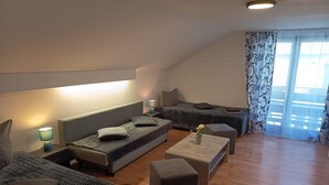 Ein modernes Hotelzimmer mit einer Couch, einem Bett, einem kleinen Tisch und einem Fenster mit Vorhängen.