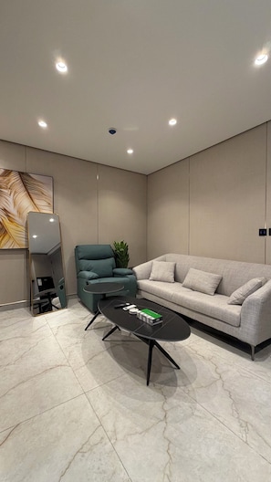 A modern living room with a sofa, a green armchair, a coffee table, and a large mirror. - 211 Tara-jre Jabal Al Lweibdeh With Stunning View (Amman)