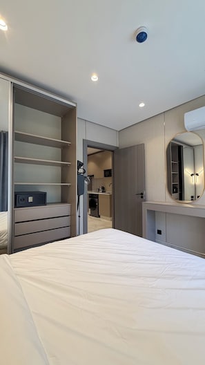 A bedroom with a bed, a wardrobe, a mirror, and a kitchenette in the background. - 211 Tara-jre Jabal Al Lweibdeh With Stunning View (Amman)