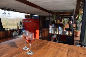 Ein Holztisch mit zwei Weingläsern, ein roter Kühlschrank und ein Bücherregal mit diversen Gegenständen.