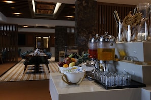 A hotel reception area with a fruit bowl, beverage dispensers, and a coffee machine. - SKI - Sivakavi Iconic (Puducherry)