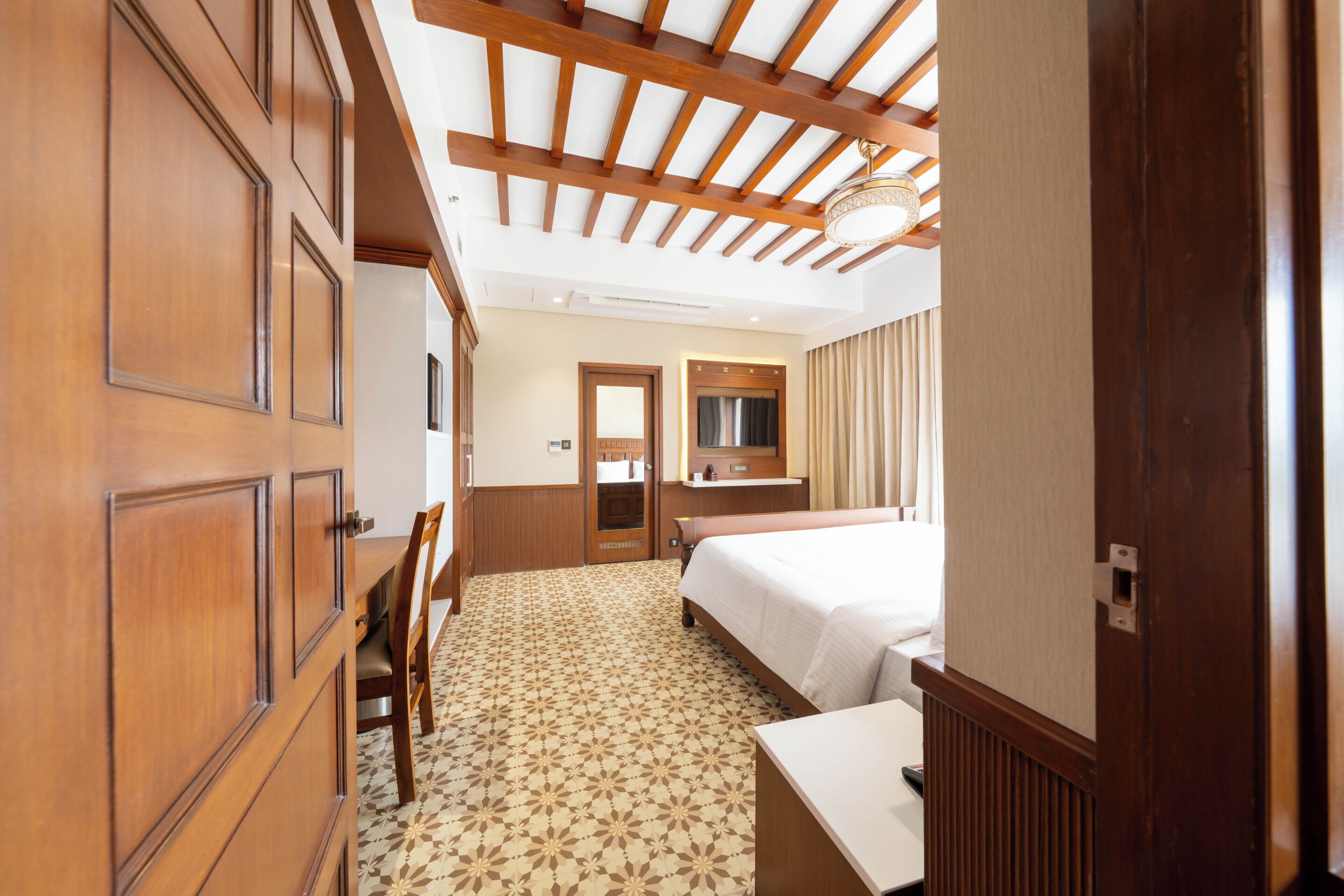 A hotel room with a bed, a desk, a chair, a wardrobe, and a mirror.