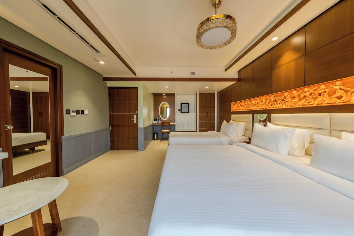 Habitación de hotel con una cama grande, una mesita de noche, un espejo y un panel decorativo en la pared.