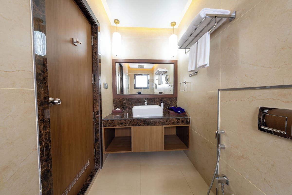 Un baño con puerta de madera, lavamanos, espejo y zona de ducha.
