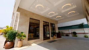 A hotel entrance with a modern design, featuring a glass facade, recessed ceiling lights, and potted plants. - SKI - Sivakavi Iconic (Puducherry)