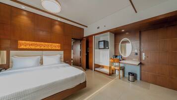 Une chambre d’hôtel moderne dotée d’un grand lit, d’une coiffeuse avec miroir, d’un petit bureau et d’un dressing.