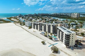 A beachfront hotel with multiple floors, a pool area, and a view of the ocean. - Tropical Beachfront 2 Bed/2Bath Carlos Pointe Condo 131, White Sandy Beach (Fort Myers Beach)