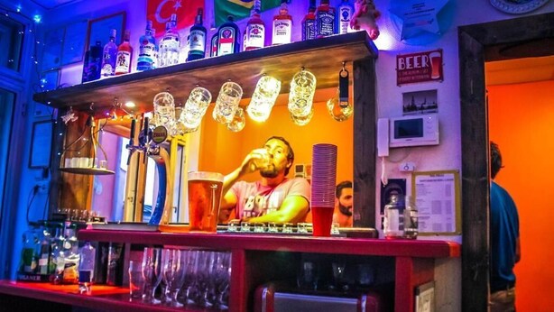 Zona de bar con una máquina de Coca-Cola, diversas botellas de licor y una persona sirviendo.