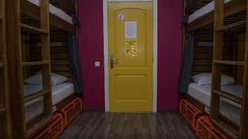 Ein Zimmer mit Etagenbetten, einer gelben Tür und orangefarbenen Körben.