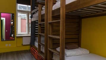 A dormitory room with bunk beds, a window, and a mirror.