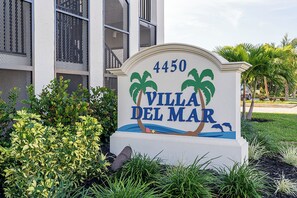 Schild für Villa Del Mar mit der Nummer 4450, Palmen und einer Strandkulisse.