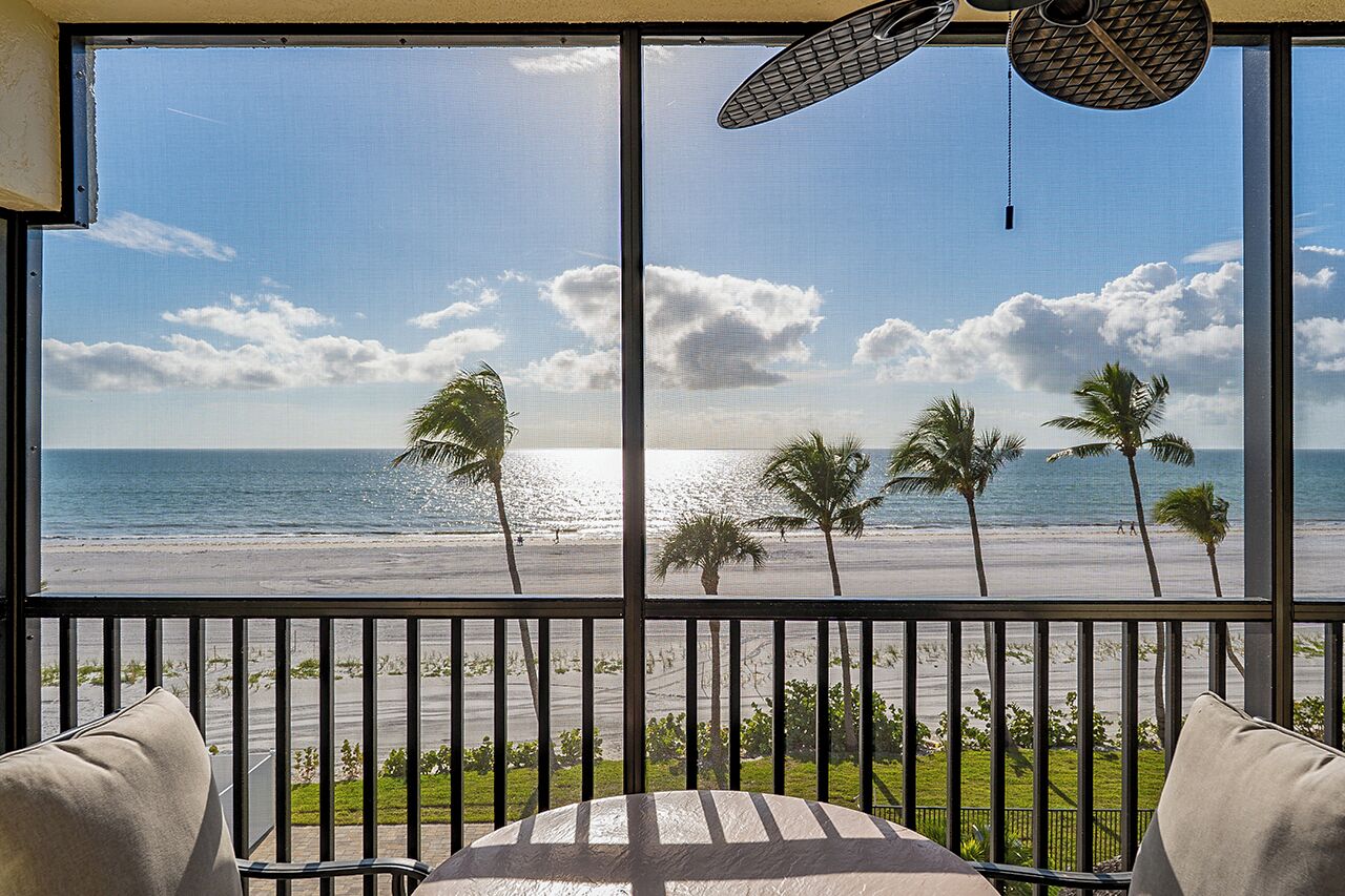 Un balcon avec vue sur la plage, les palmiers et l’océan.
