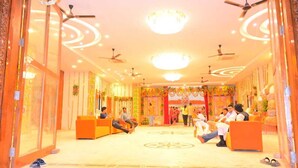 A hotel lobby with seating areas, ceiling fans, and decorative lighting. - Shree Videhi Atithi Grah (Samudrapur)