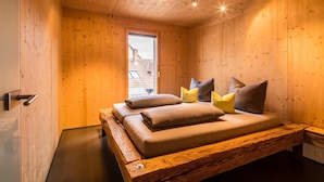 Une pièce de cabane en bois comprenant un lit, des oreillers et une fenêtre.