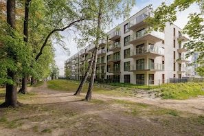 A multi-story residential building with balconies, surrounded by trees and a dirt path. - Unique Studio for 2 People | Spacious Balcony (Katowice)