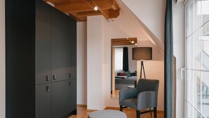 A modern interior with a dark wardrobe, a grey armchair, a small ottoman, and a floor lamp. - Muskatellerhaus Holiday Home with Shared Pool, Private Terrace, and Wi-Fi (Auggen)