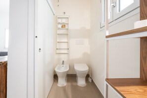 Ein kleines Badezimmer mit integriertem Bidet, Toilette und Ablagefläche für Toilettenartikel.