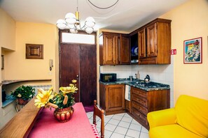 Eine kleine Küche mit Holzschränken, einer Mikrowelle und einem Essbereich mit Tisch und Stühlen.