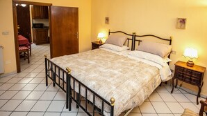 Une chambre à coucher avec un lit, des tables de chevet, une lampe, une porte et une petite table avec des chaises.