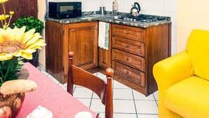 Une cuisine avec des armoires en bois, un four à micro-ondes, un évier et une chaise jaune.