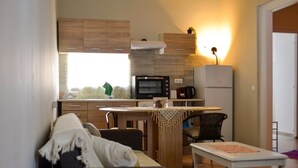 A compact kitchen with a microwave, stove, and refrigerator. There is a dining area with a table and chairs. - Kerameikos Radio-Apartments (Athina)