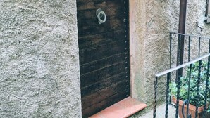 Un bâtiment rustique en pierre, doté d’une porte en bois, d’un portail en métal et d’un petit marchepied menant à l’entrée.