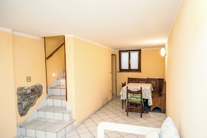 Una habitación con escalera, una mesa de comedor con sillas y una ventana.