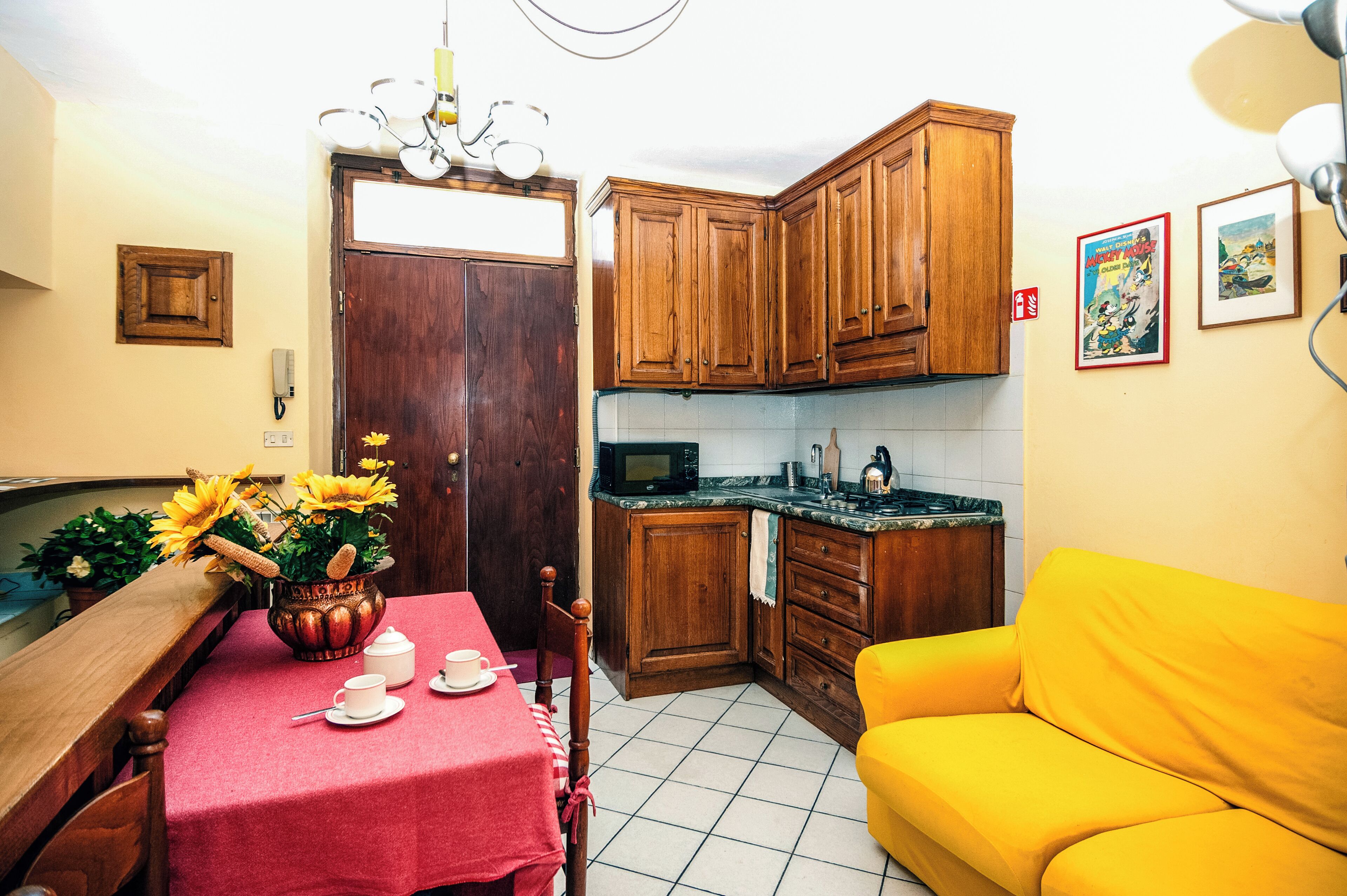 Une cuisine compacte dotée de meubles en bois, d’un four à micro-ondes et d’un coin repas avec une table dressée pour deux personnes.